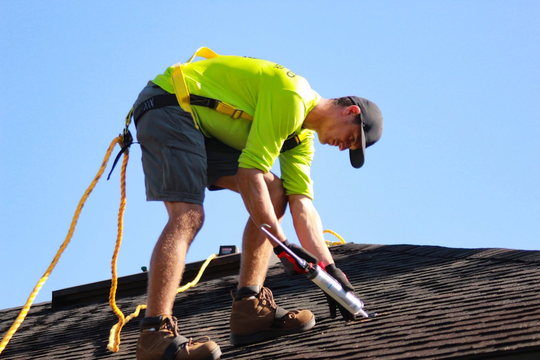 a man in a yellow shirt is working on a roof a man in a yellow shirt is working on a roof